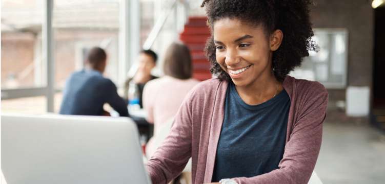 Photo of a person smiling in front of a laptop 