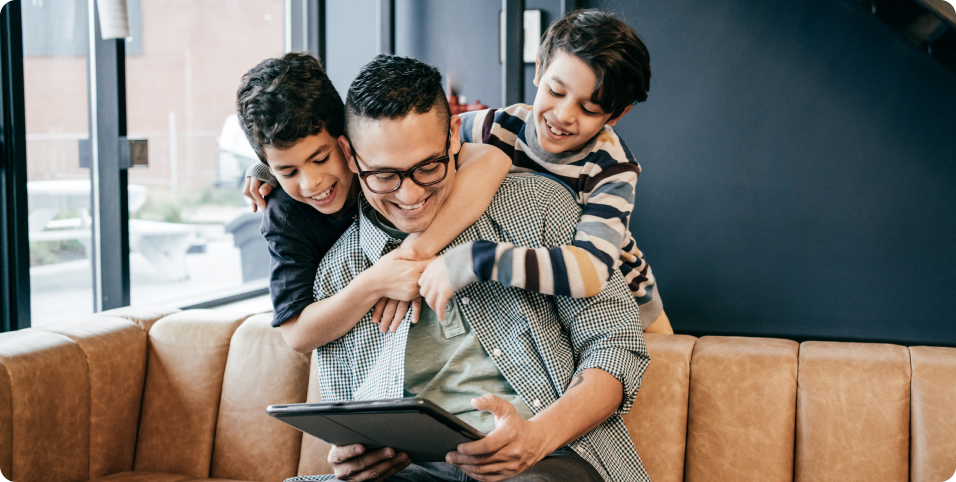 Photo of a parent sitting on a couch playing with their two children