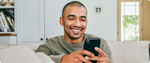 Photo of a man looking at his mobile phone in his living room