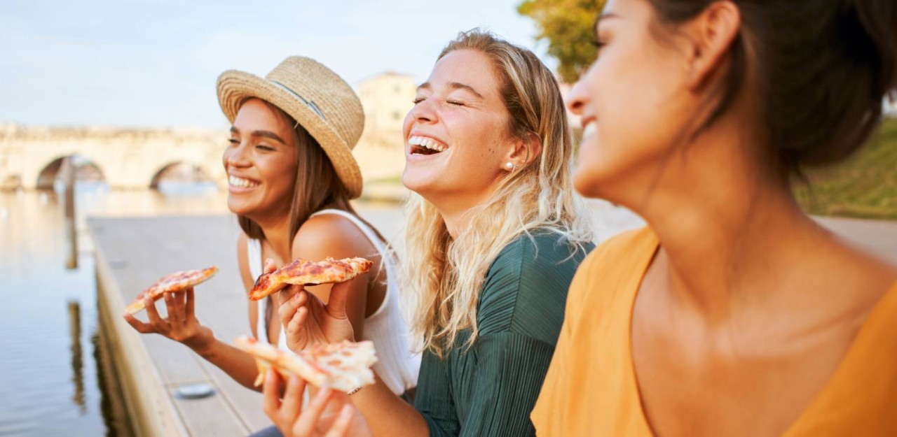 Photo of three people smiling and eating together