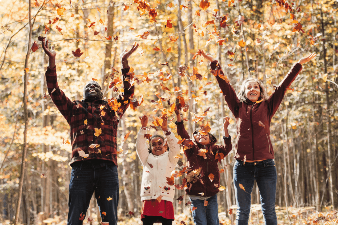 Photo d’une famille jouant avec des feuilles dans la forêt