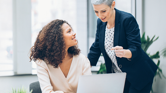 Photo of a woman speaking to another woman who is sitting down
